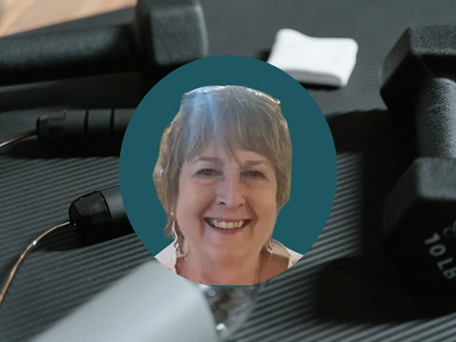Judi, a NatFitPT client, in a portrait photo with gym equipment in the background